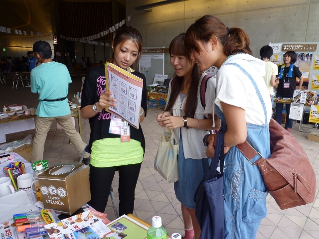 国内NPOインターンシップで留学生がイベント会場の来場者に活動を説明する様子